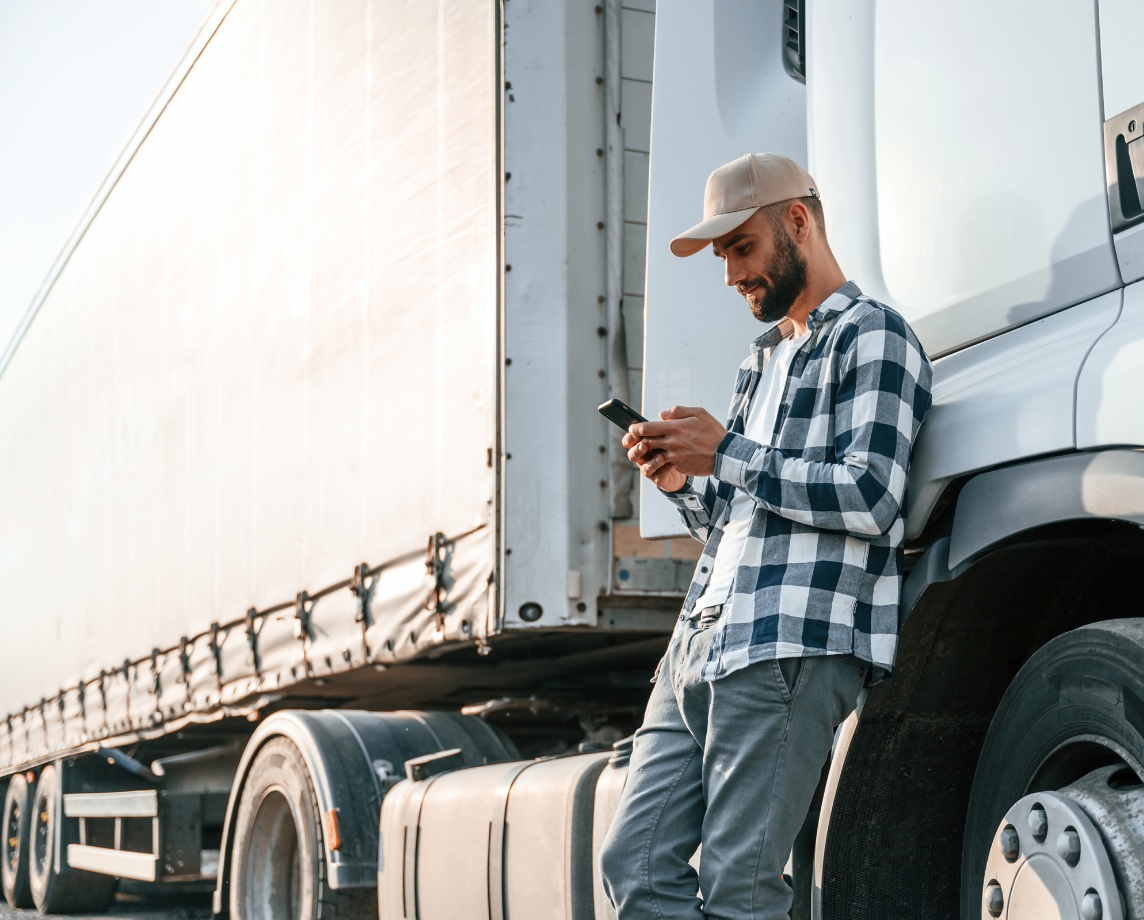 An owner-operator checking his phone next to his truck